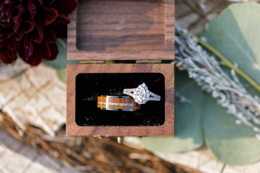 Wedding rings displayed in a rustic wooden box with diamond engagement ring and wood inlay band.