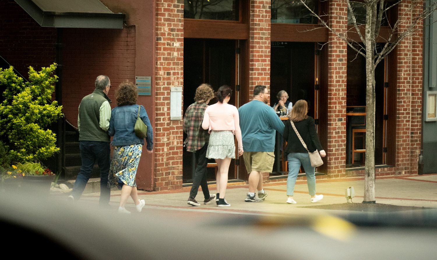 Group of people gathered outside brick building entrance.