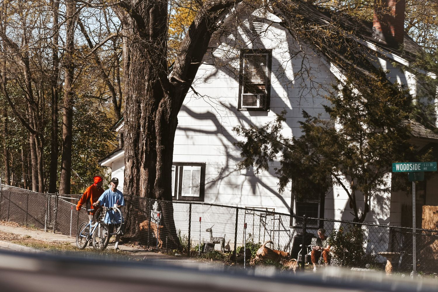 A white cottage-style house with pitched roof visible through autumn trees.