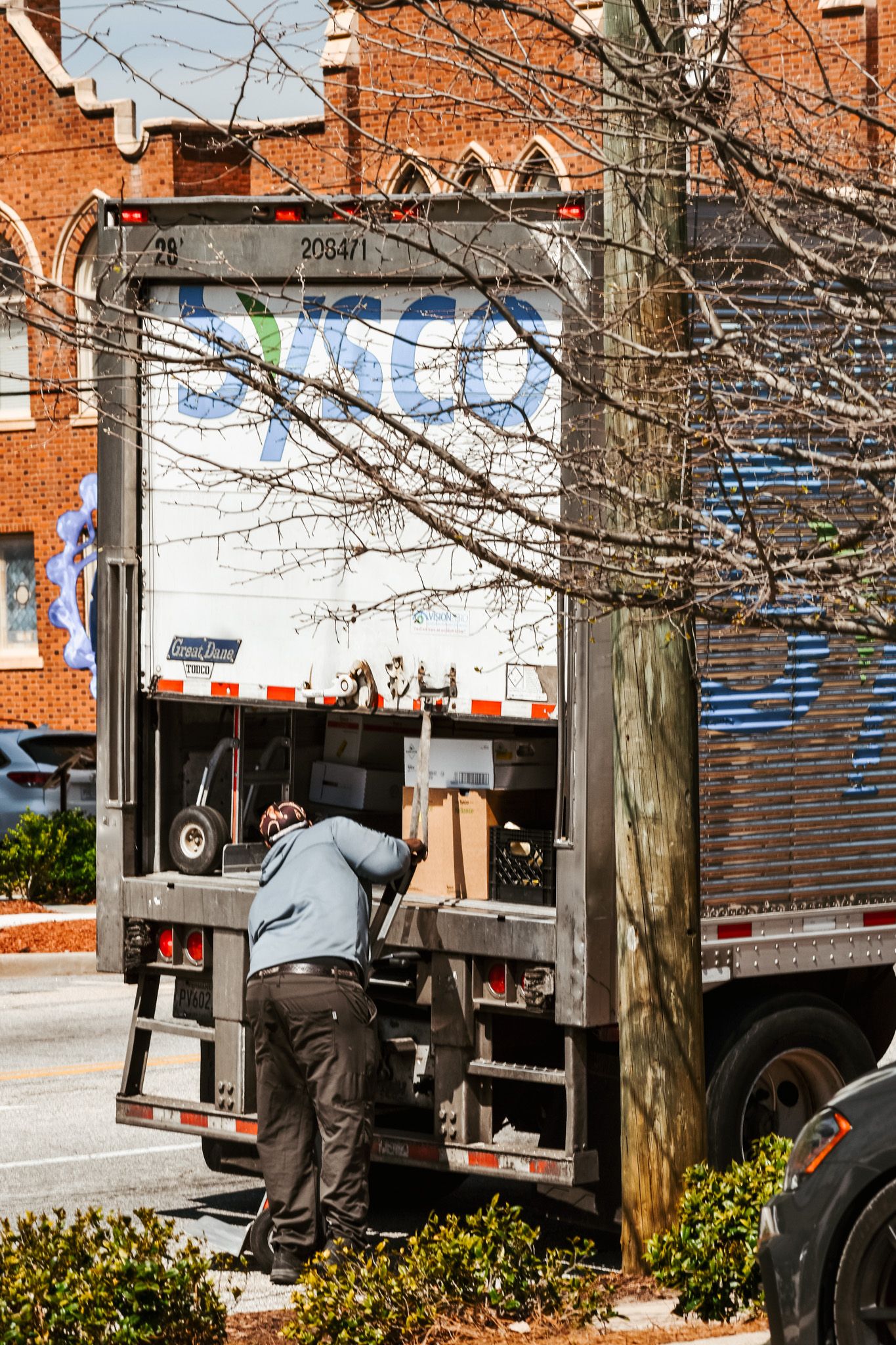 A delivery worker unloading boxes from the back of a commercial truck on a city street.