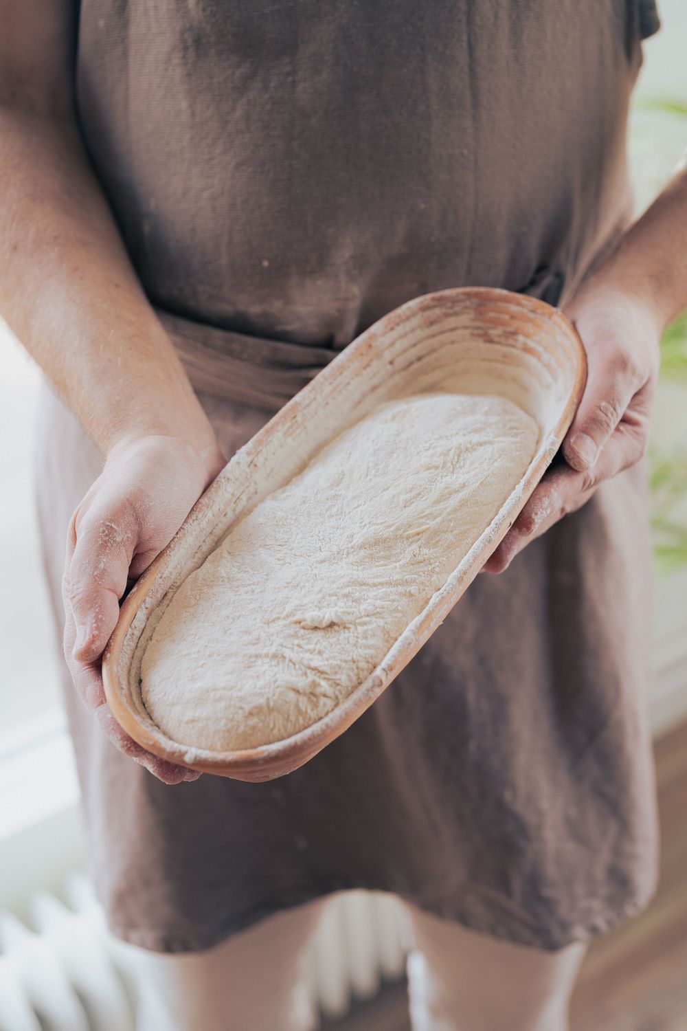 Portrait of a baker holding fresh artisanal bread in a bakery. Ideal for food branding, restaurant marketing, and promotional materials.