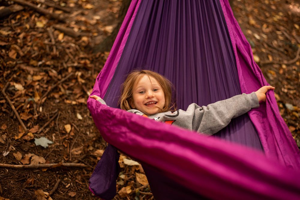 Happy relaxation in a bright purple hammock outdoors.