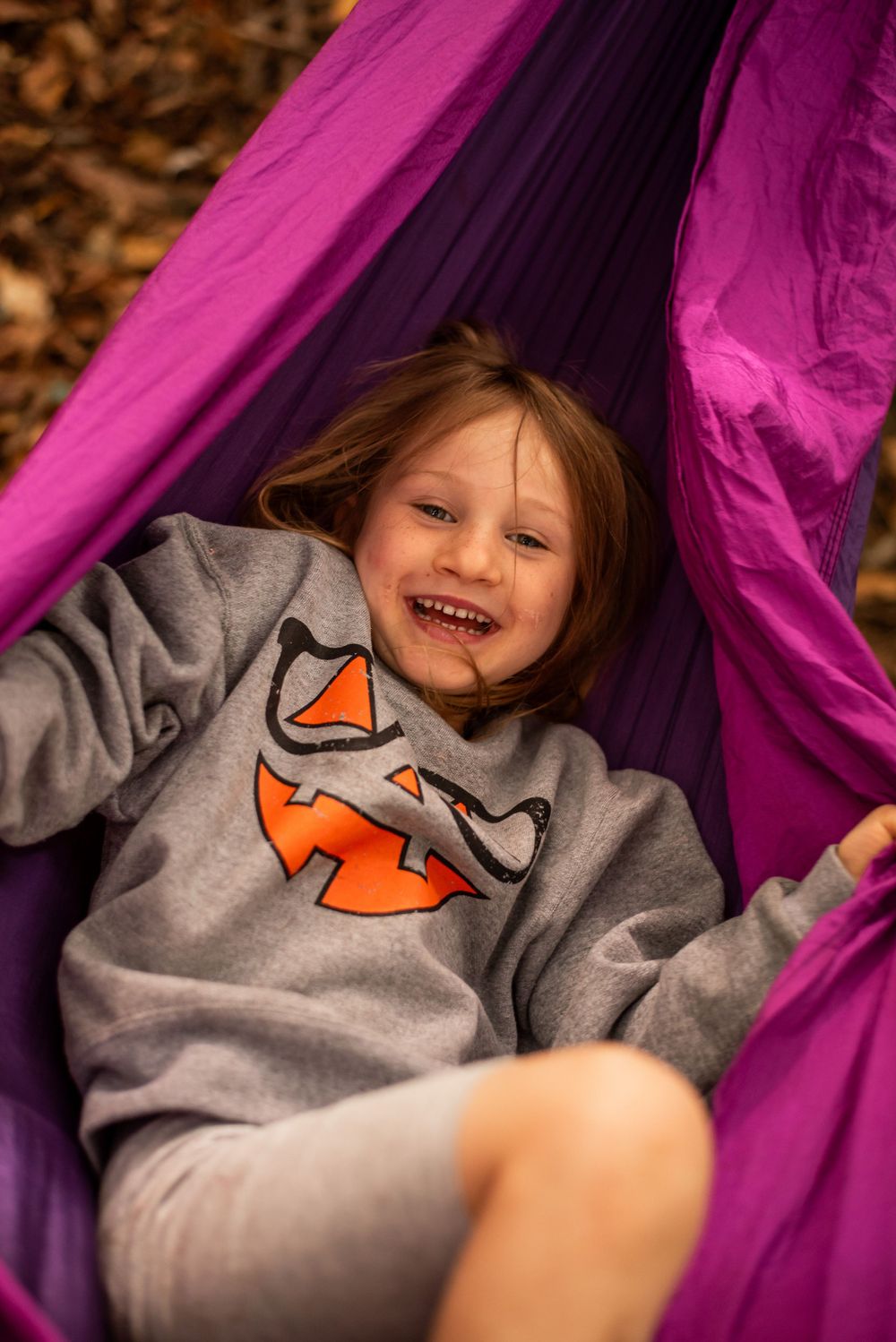 Cheerful moment captured in a vibrant purple hammock.