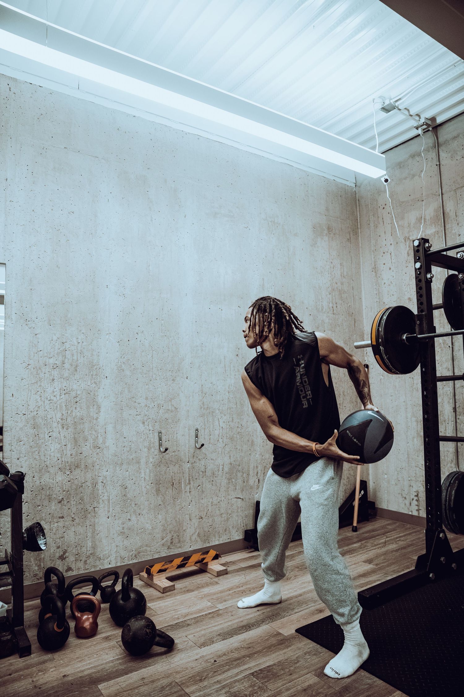 Weightlifter performing row exercise with barbell in minimalist gym space.