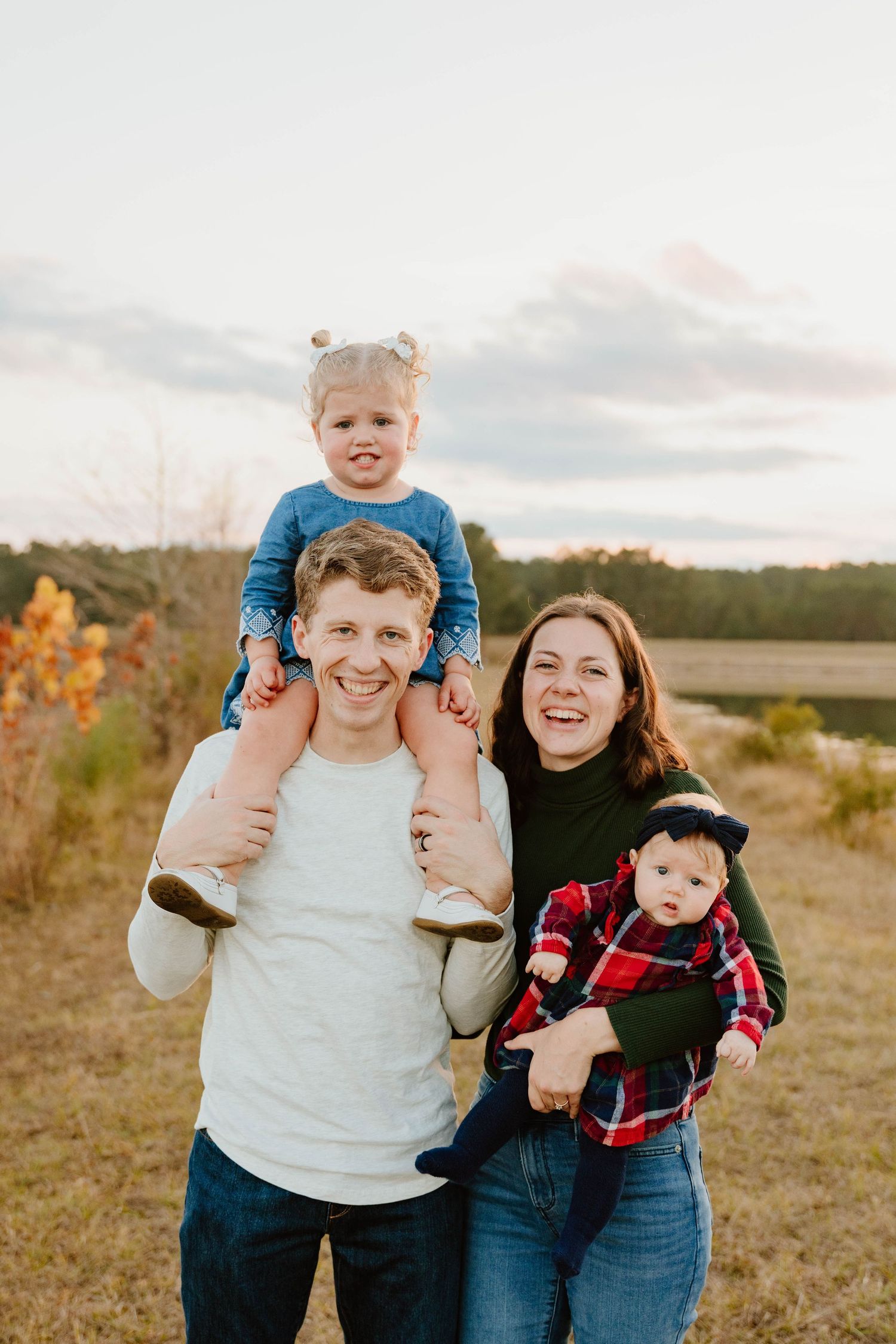 Family portrait session in a field during golden hour with casual autumn outfits.