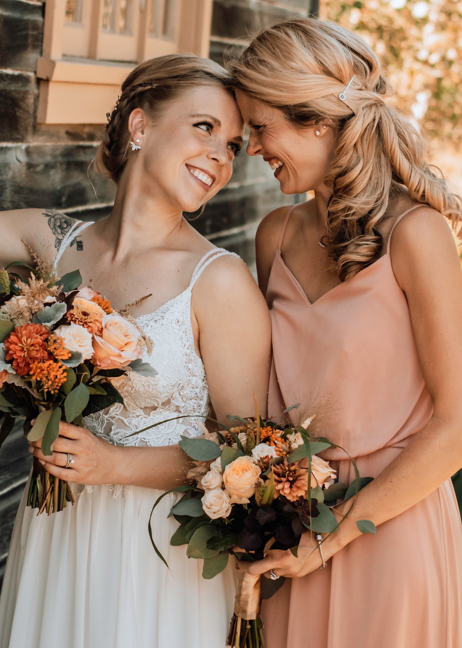 Wedding party members sharing joyful moment with orange and peach bouquets.