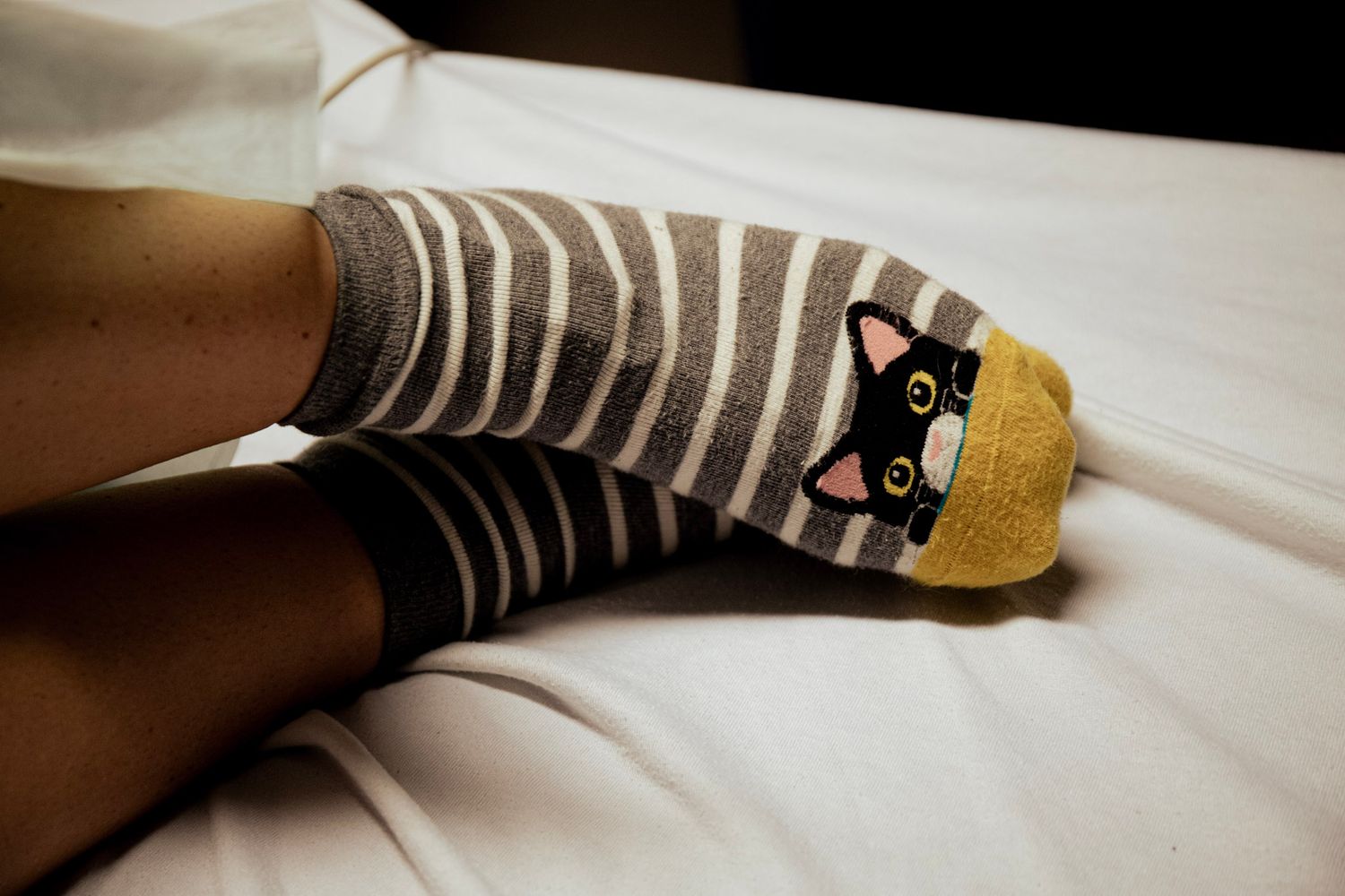 Grey and white striped socks with yellow toes shown against white bedding. Mother in labor details.
