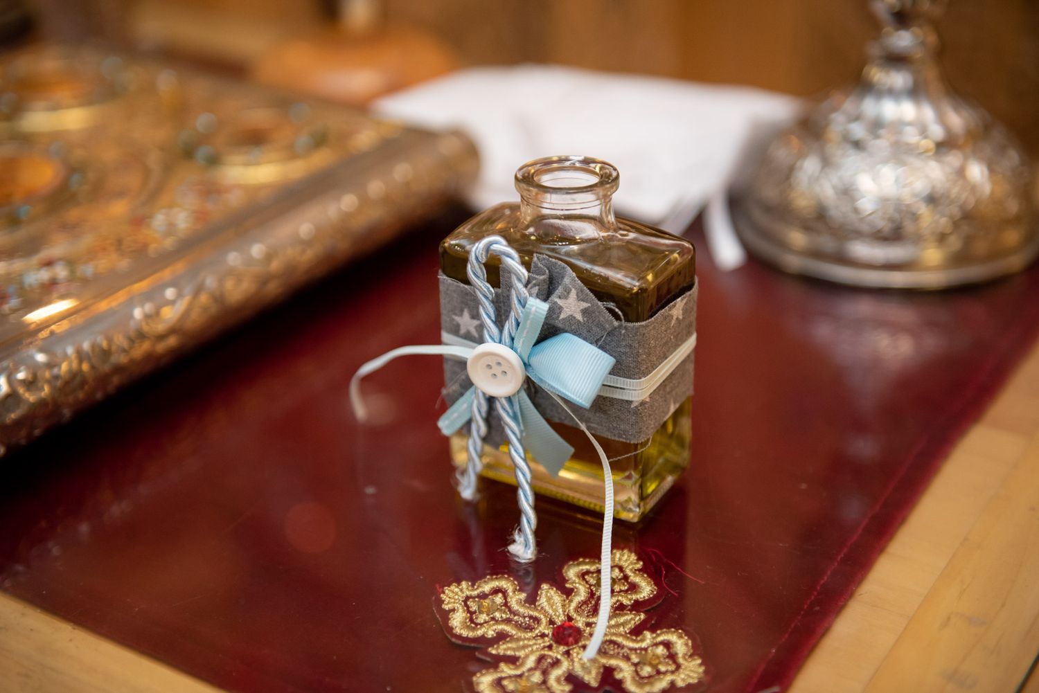 Small decorative glass bottle with blue ribbon bow on a church altar.