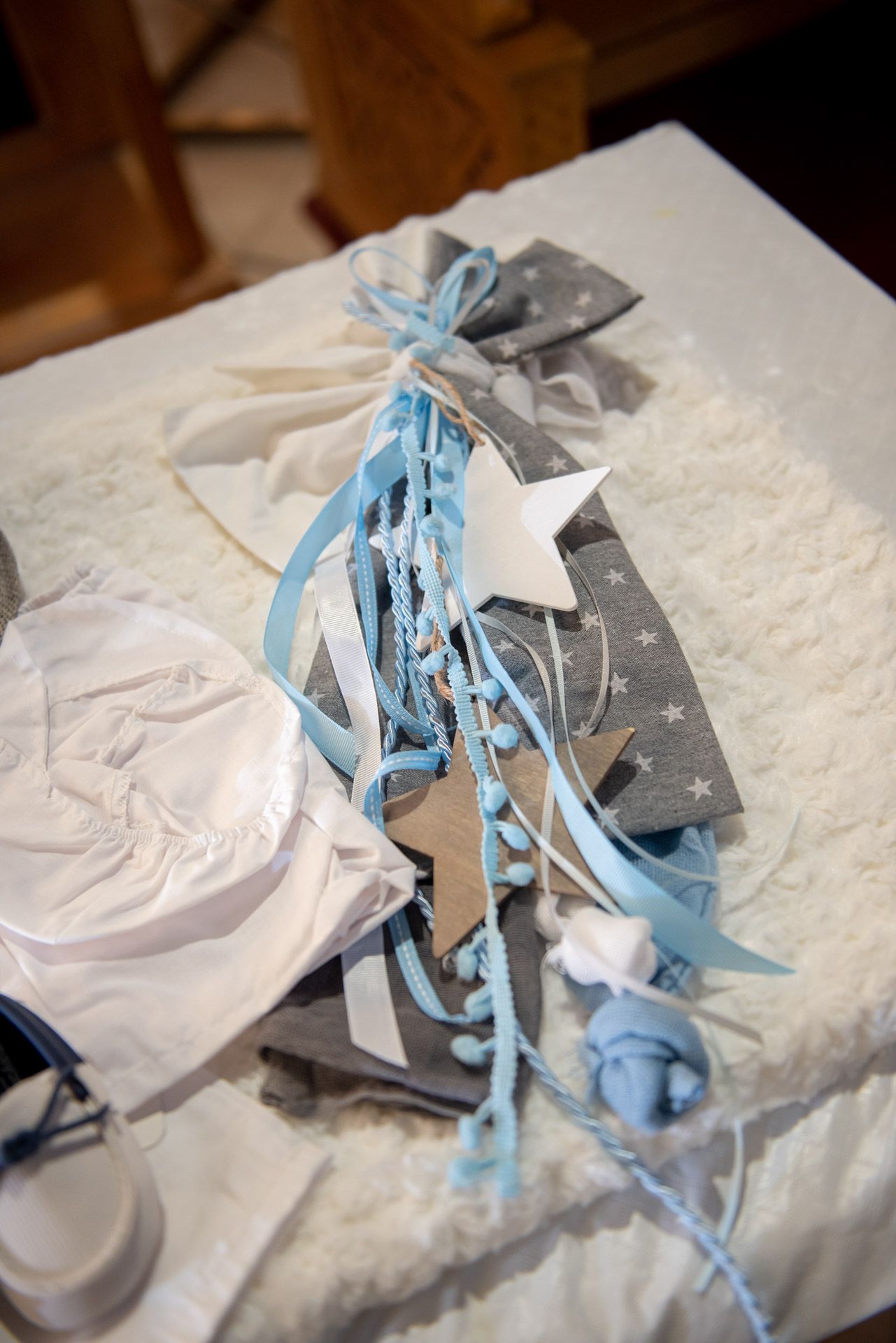 Blue and gray baptism decorations with ribbons, stars, and beads arranged on a white surface.