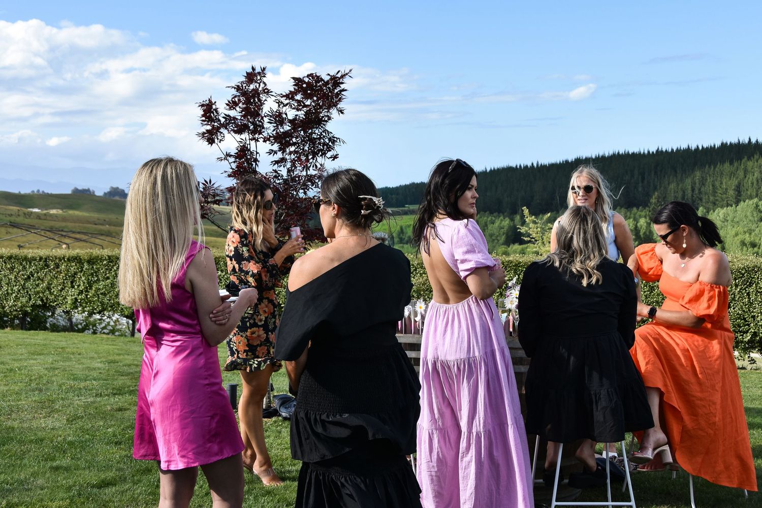 Women in colorful dresses socializing outdoors on a sunny day.