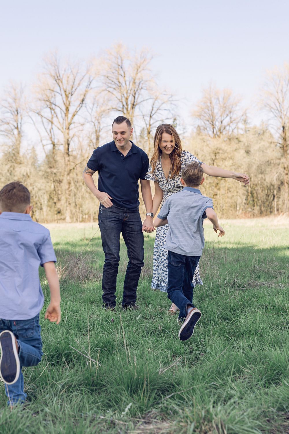 A happy family of four plays together in a green field on a sunny day.