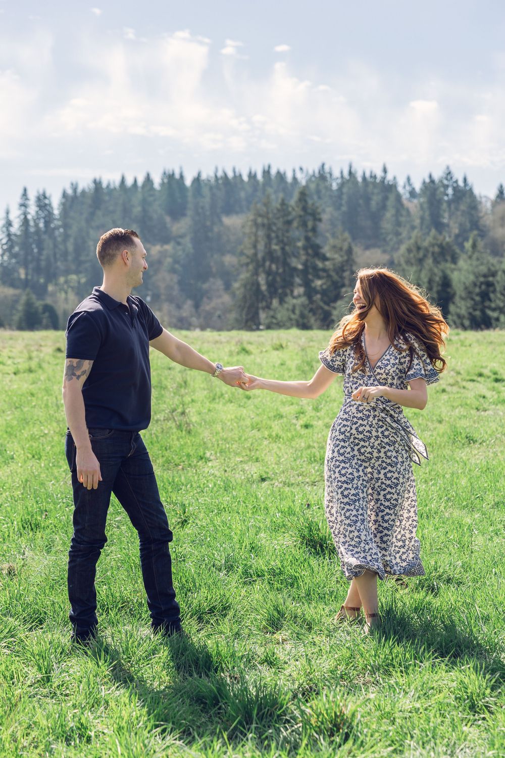 Couple holding hands and walking together across a lush green meadow on a bright sunny day.