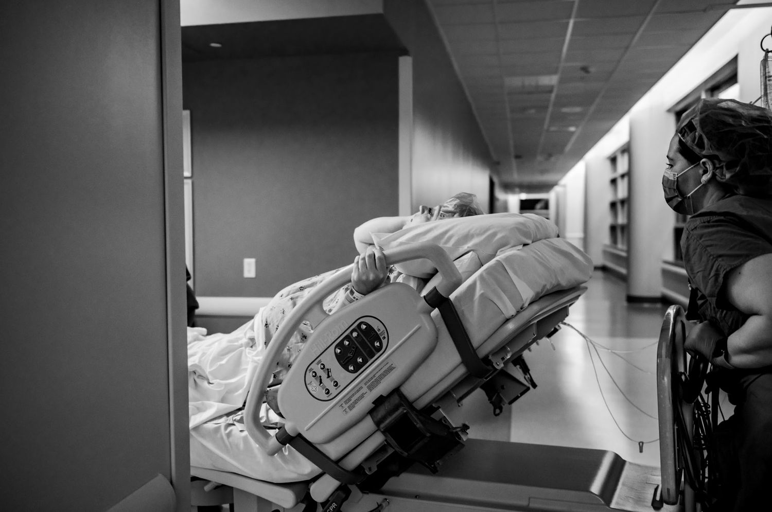 Hospital stretcher being moved through a dimly lit corridor in black and white to OR for c-section