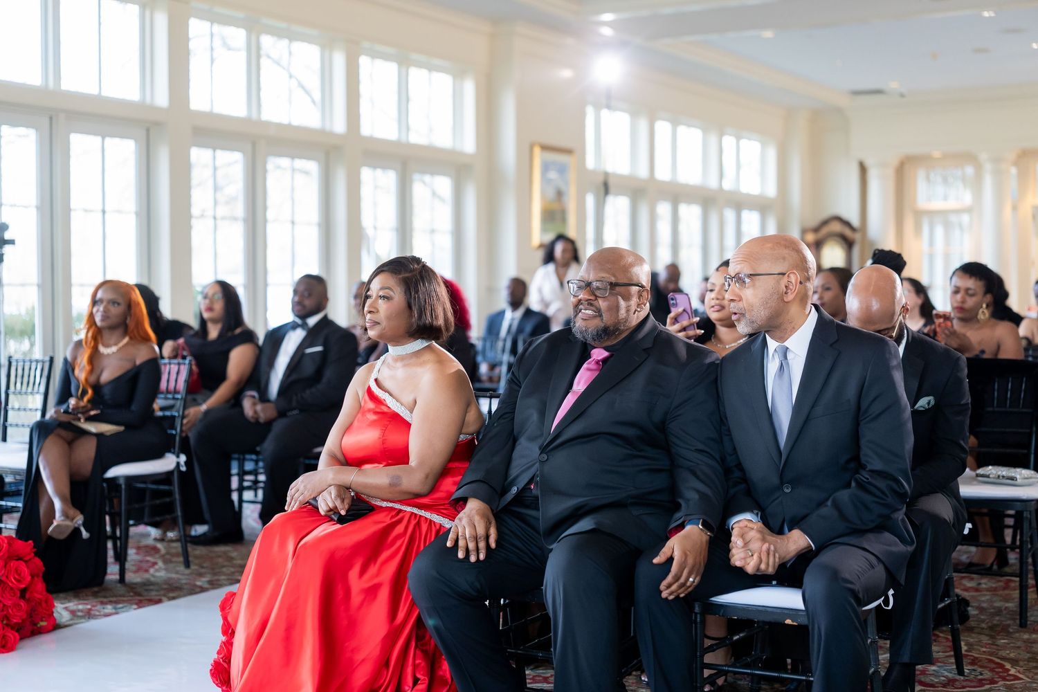 Guests in formal attire seated at an elegant wedding ceremony in a bright ballroom venue. Deerfield Golf Club Newark De