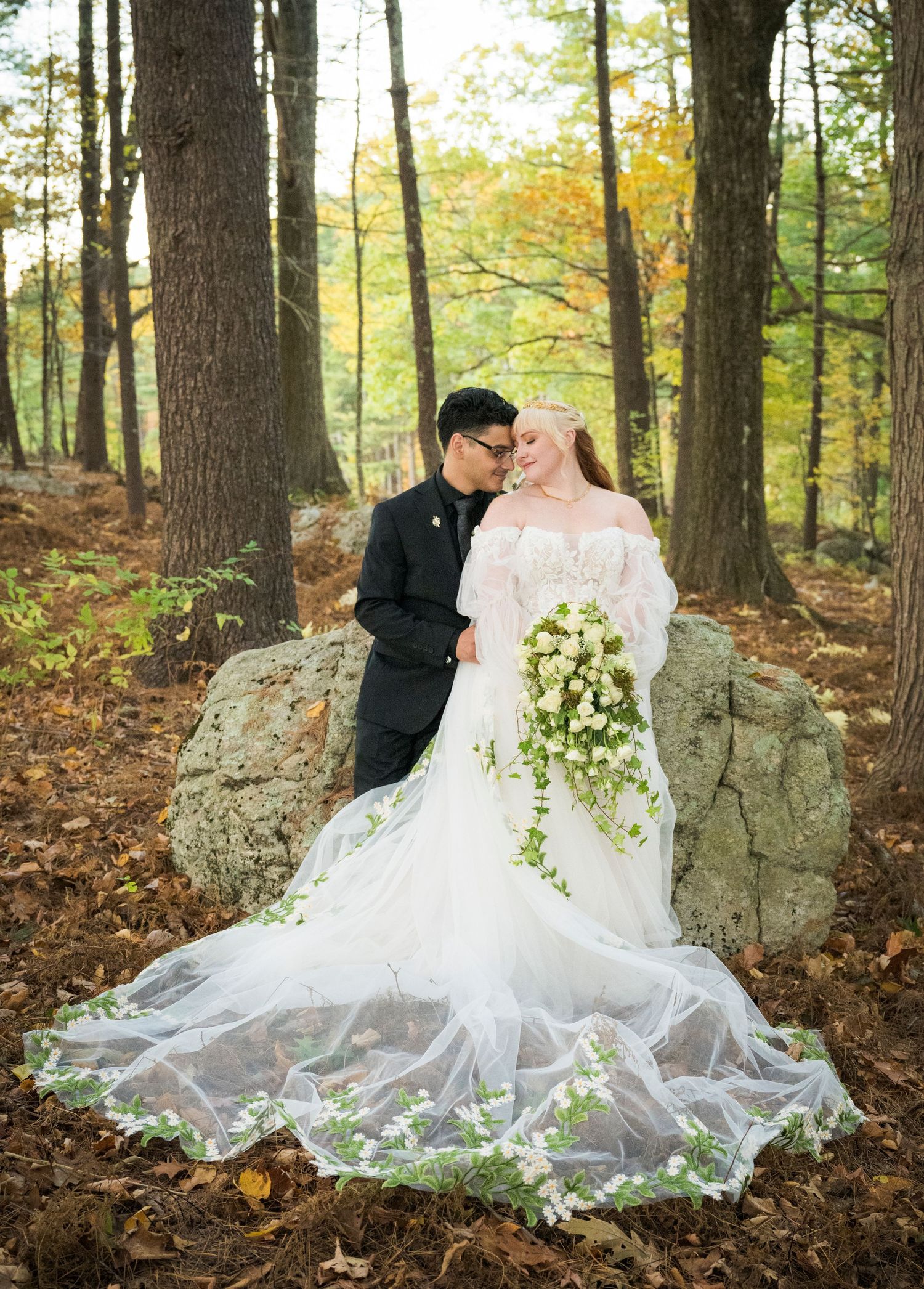 Bride and groom embracing at sunset with vibrant pink and purple sky backdrop on lush green field.