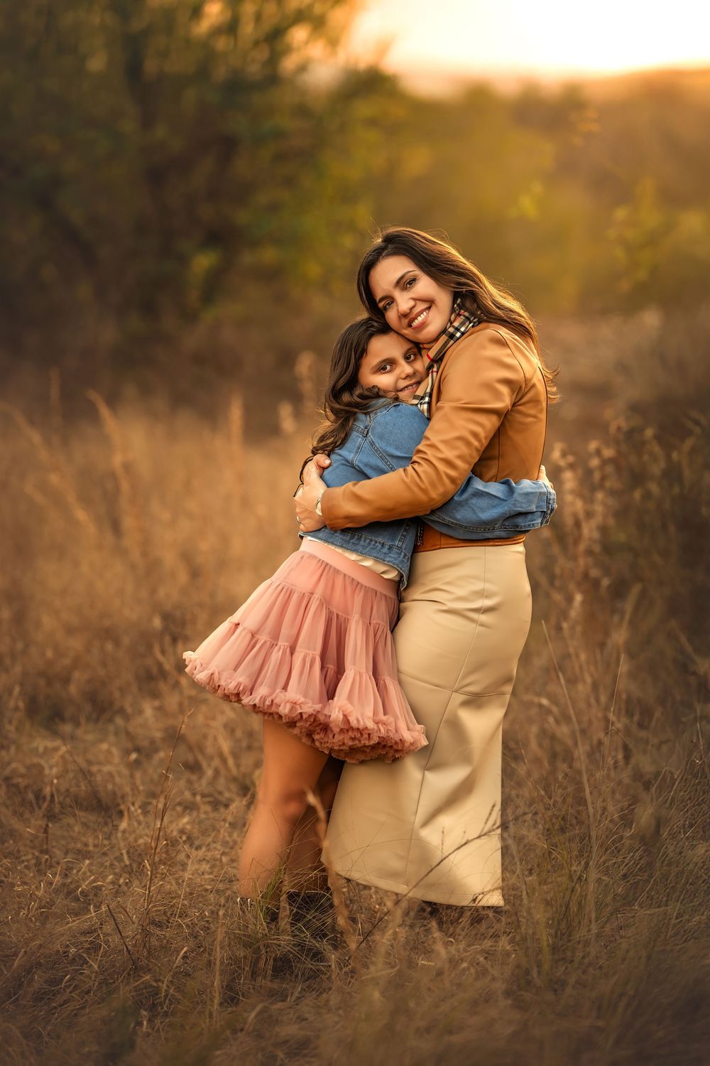 Mother and daughter hugging warmly in a golden field during autumn sunset photo session with Marietta photographer.