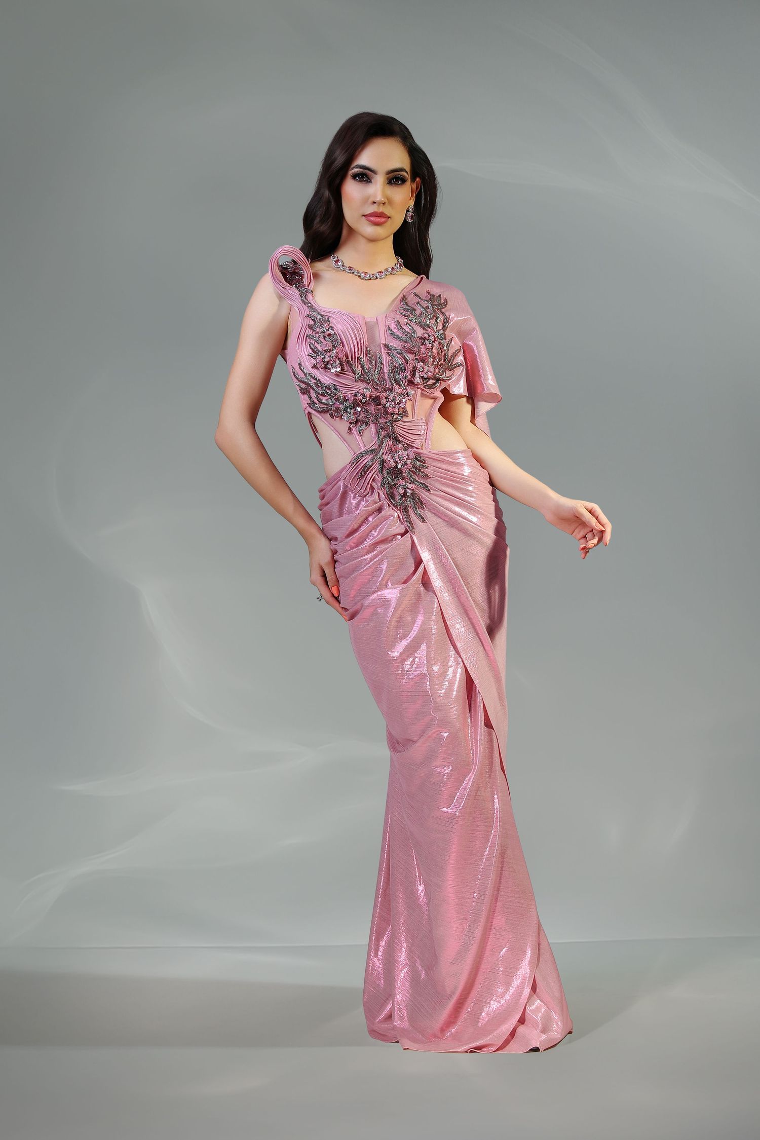 Woman in pink sequined saree gown with embellished bodice and ruffle sleeve, posing elegantly.