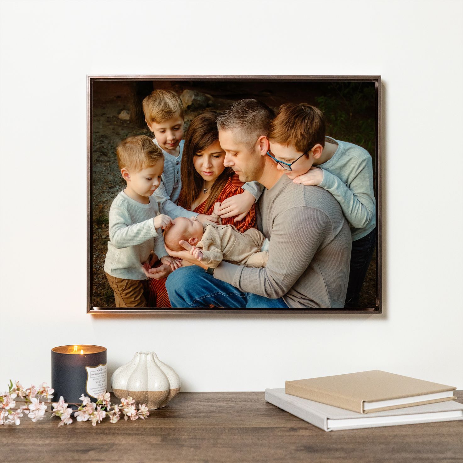 Family portrait canvas print hanging on wall, showing parents and children admiring a newborn baby in Keller, TX.