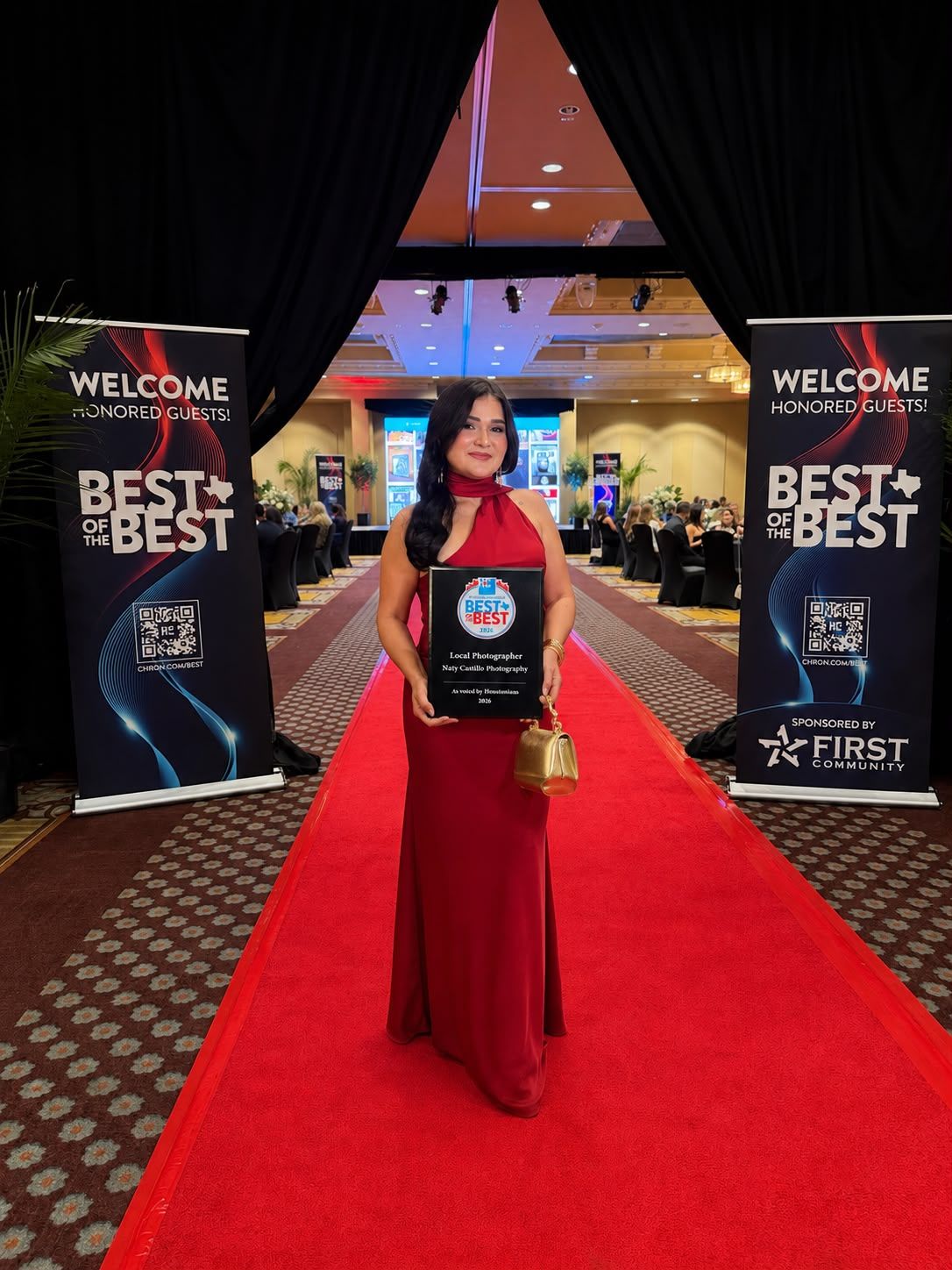 Woman in red gown holds award plaque on red carpet at Best of the Best honored guests event sponsored by First Choice.