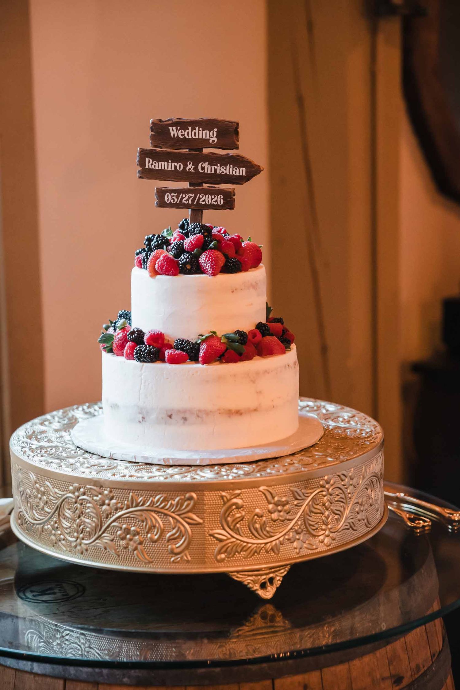 Rustic wedding cake with fresh berries and custom topper at Briar Barn Inn reception