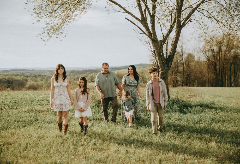Family of six walking in a green meadow near a bare tree on a sunny spring day. indiana pa family photography, pittsburgh photographer,