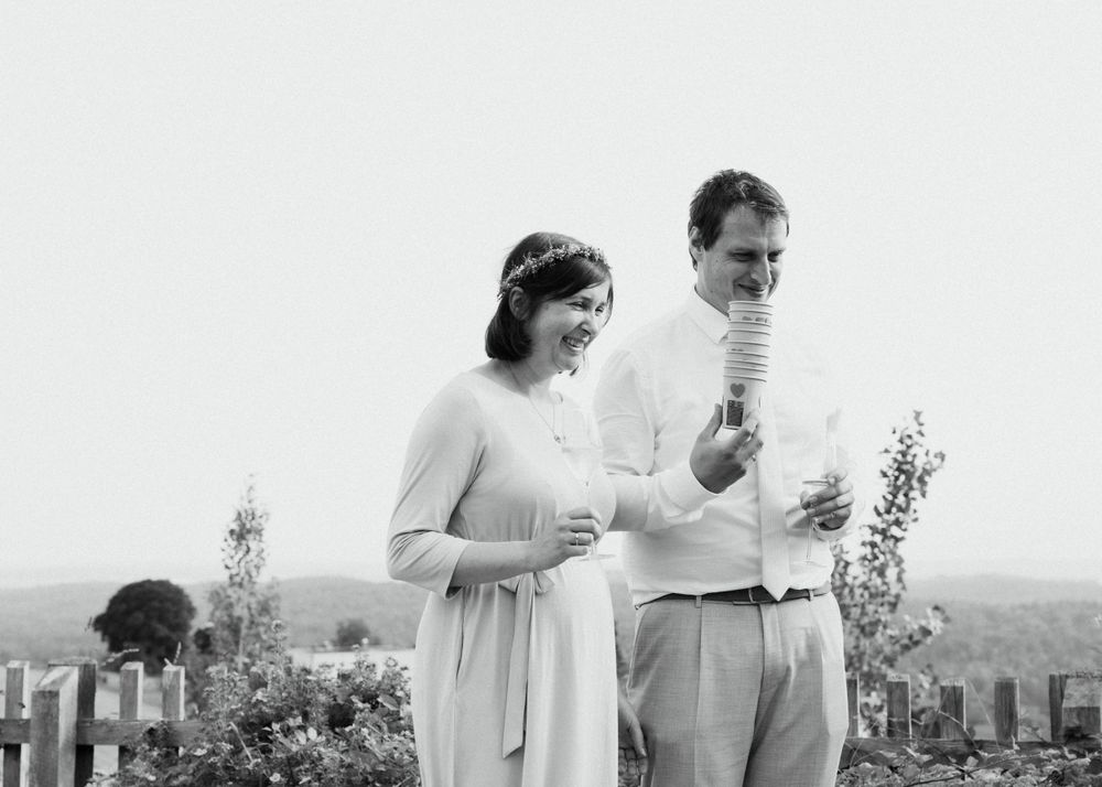 Hochzeitsfotografie, Brautpaar steht nebeneinander und ist in Interaktion mit den Gästen, schwarz-weißes Bild