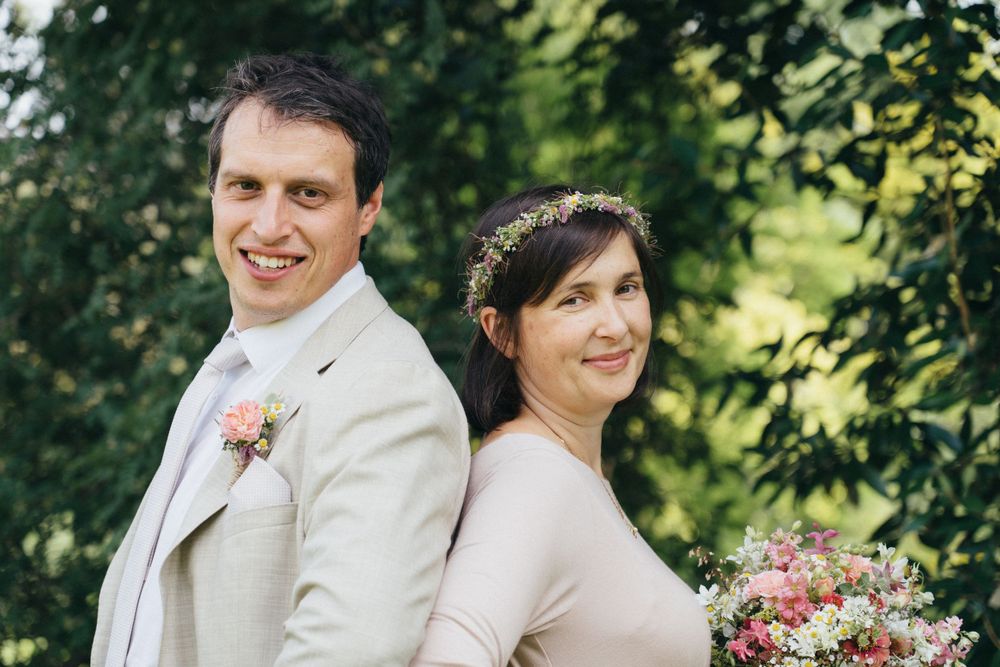 Paarshooting am Hochzeitstag, Brautpaar steht Rücken an Rücken und schaut direkt in die Kamera