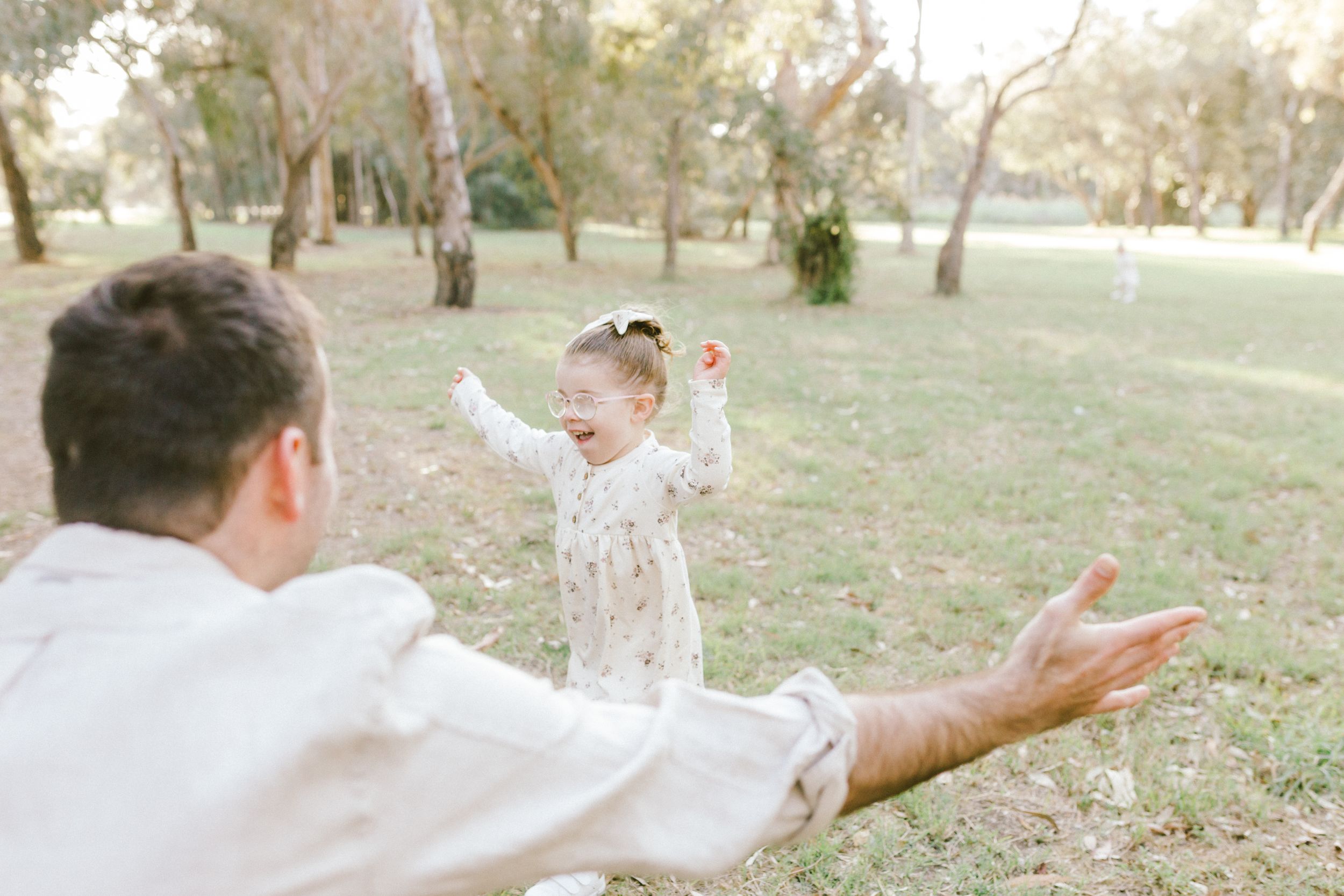 A couple enjoying a sunny day outdoors while spinning around playfully together in a grassy field.