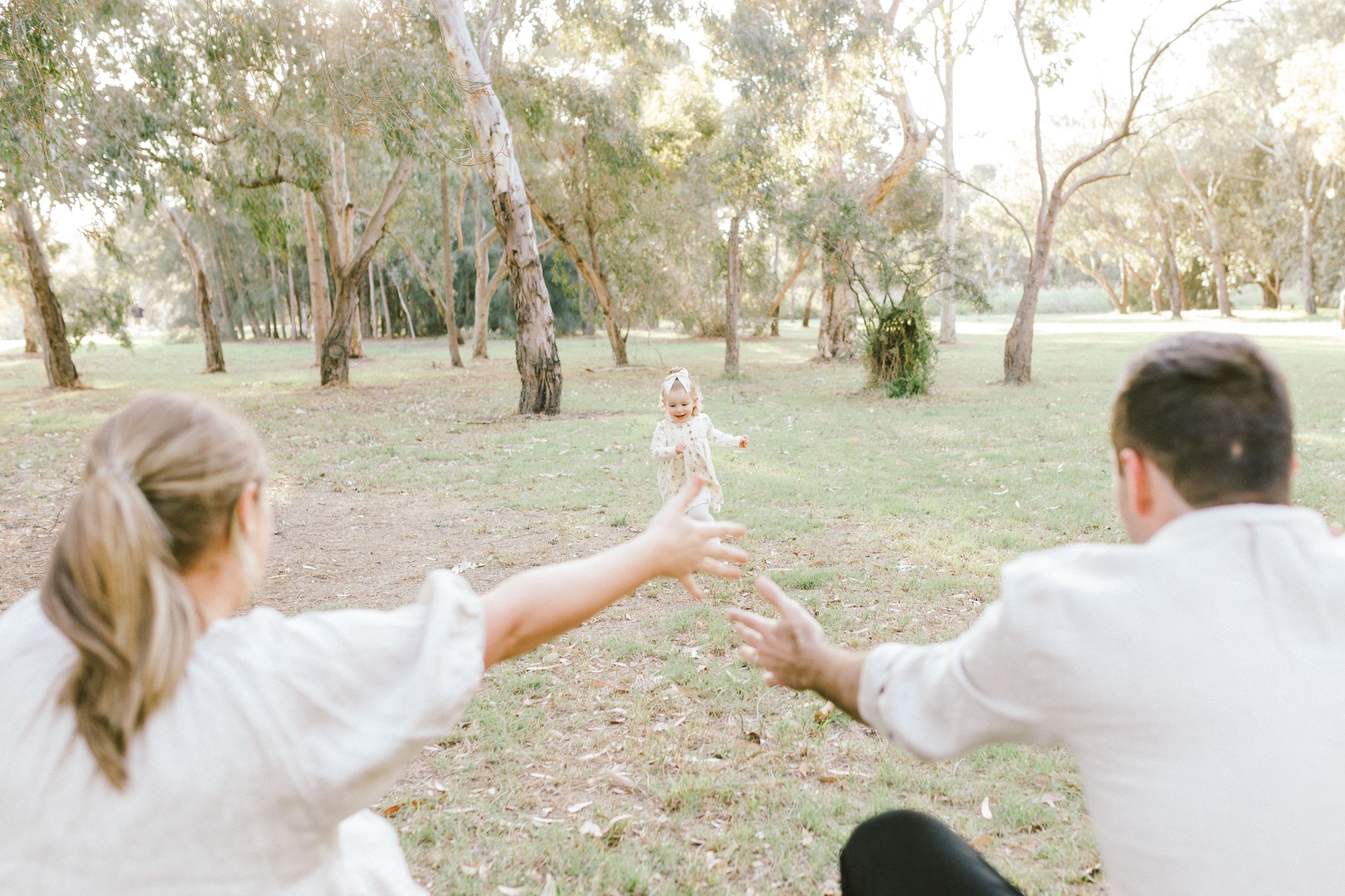 A group of people wearing white clothing dance in a circle outdoors in a natural setting.