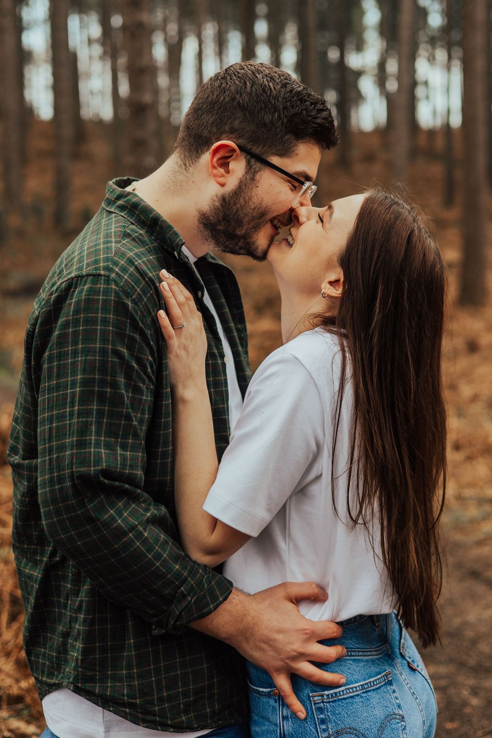 A loving couple sharing an intimate moment together in a wooded forest setting during autumn.