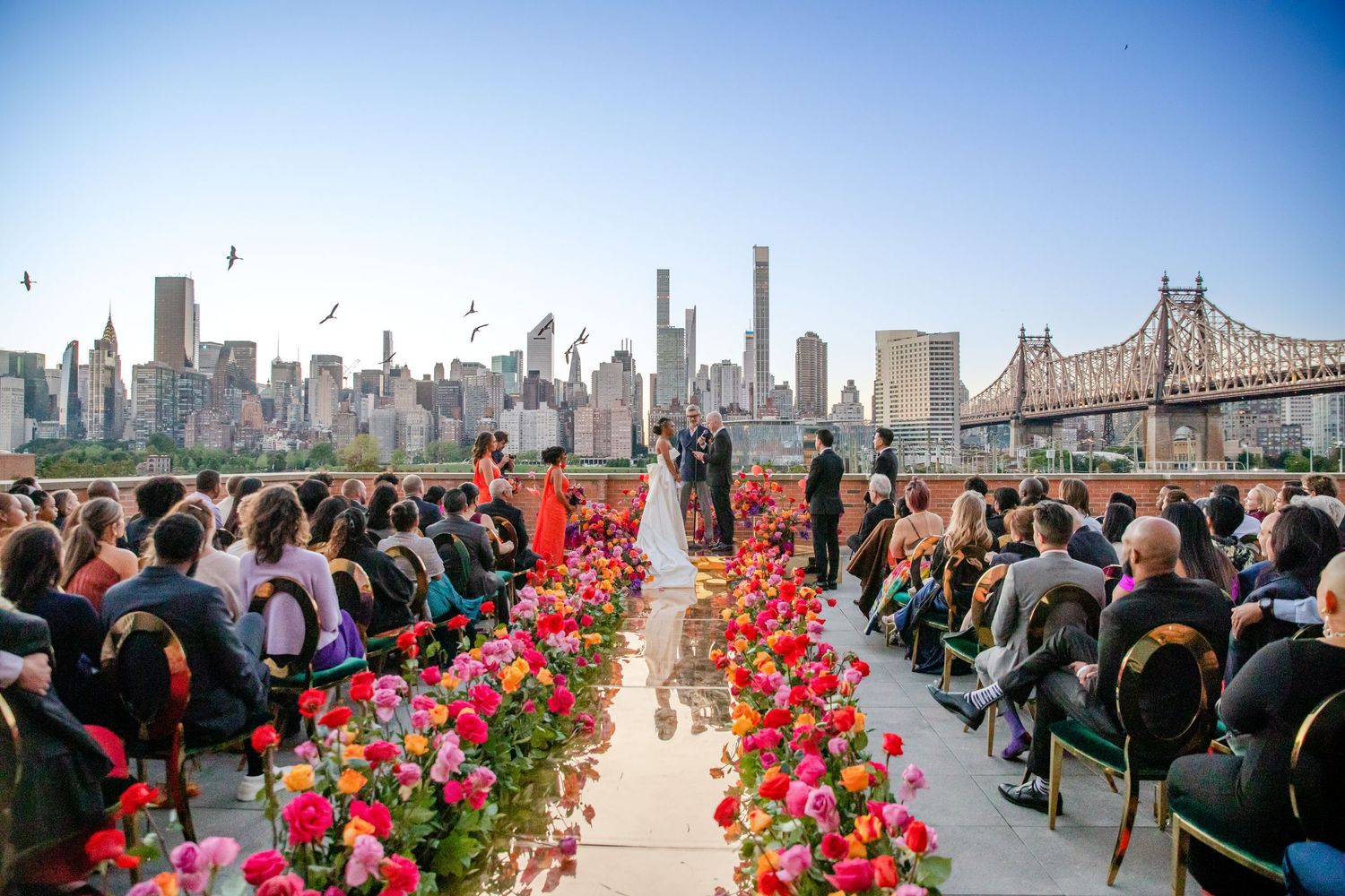 Rooftop wedding ceremony setup with Manhattan skyline backdrop and red floral aisle runner.