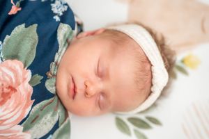 Sweet newborn photo with navy floral backdrop and soft pink rose details. Quad Cities Newborn Photography