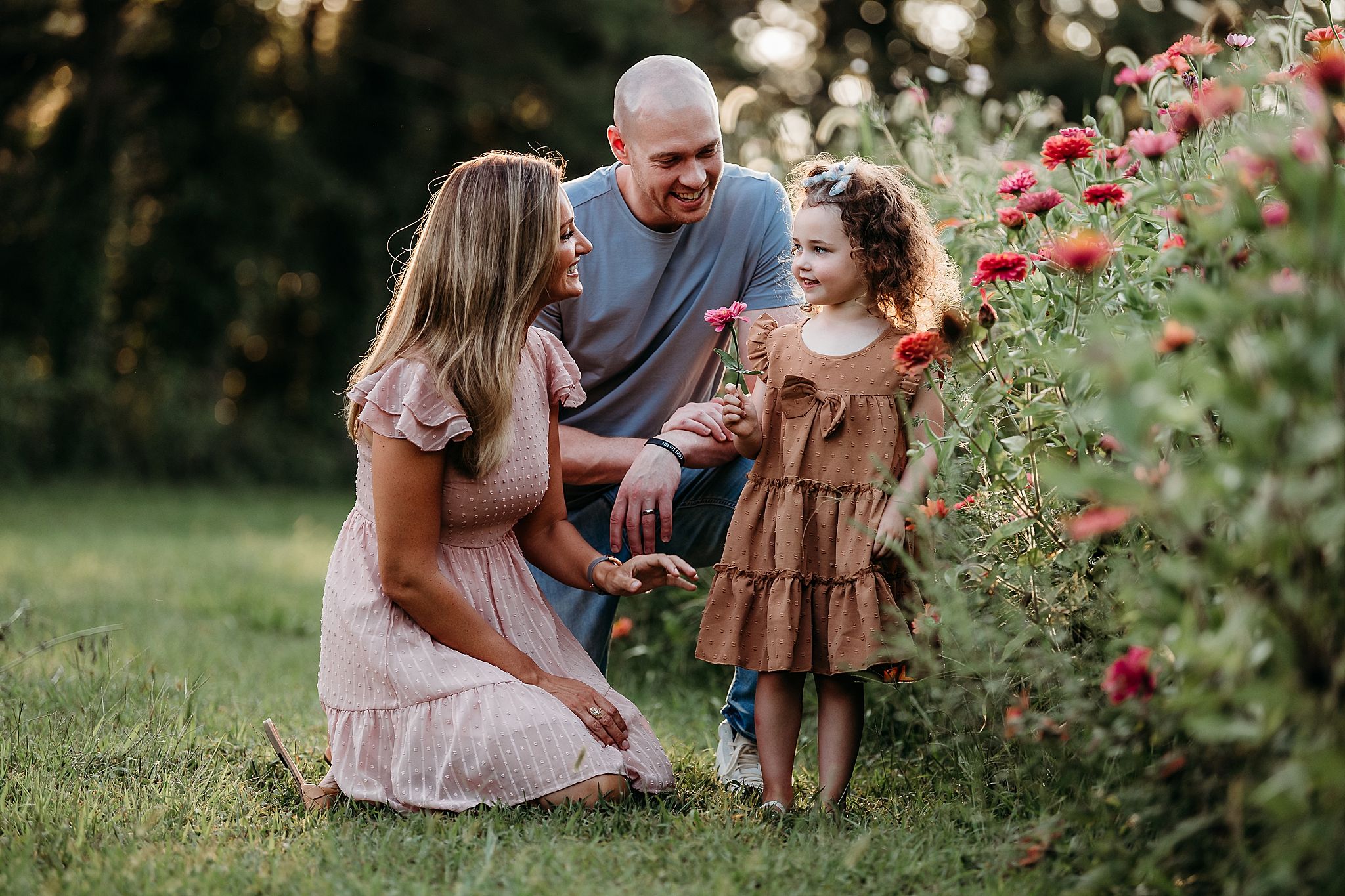 Loving family moment captured in a garden with blooming red flowers during golden hour.