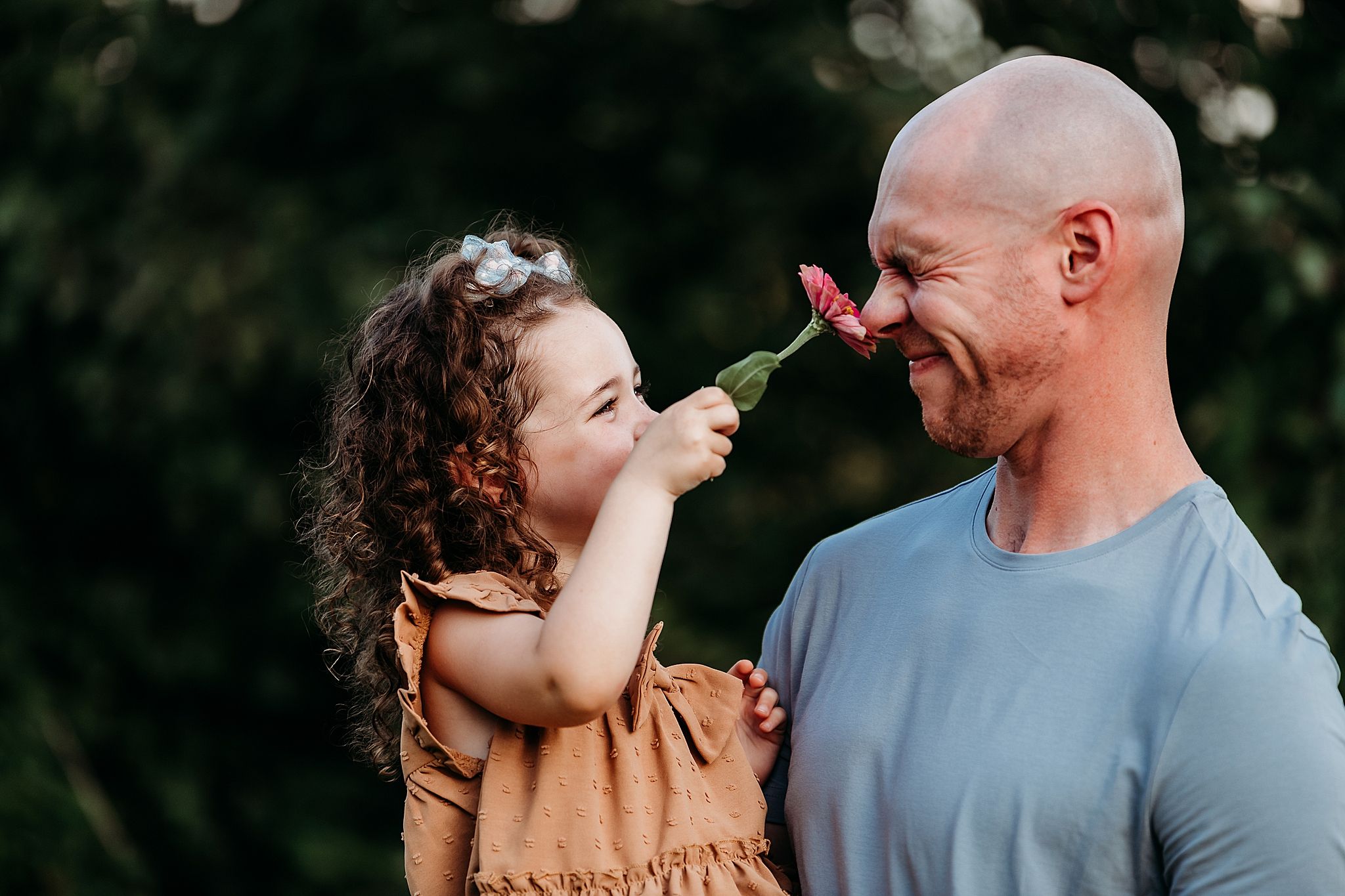 A joyful moment shared between parent and child playing with their noses in an outdoor summer setting.
