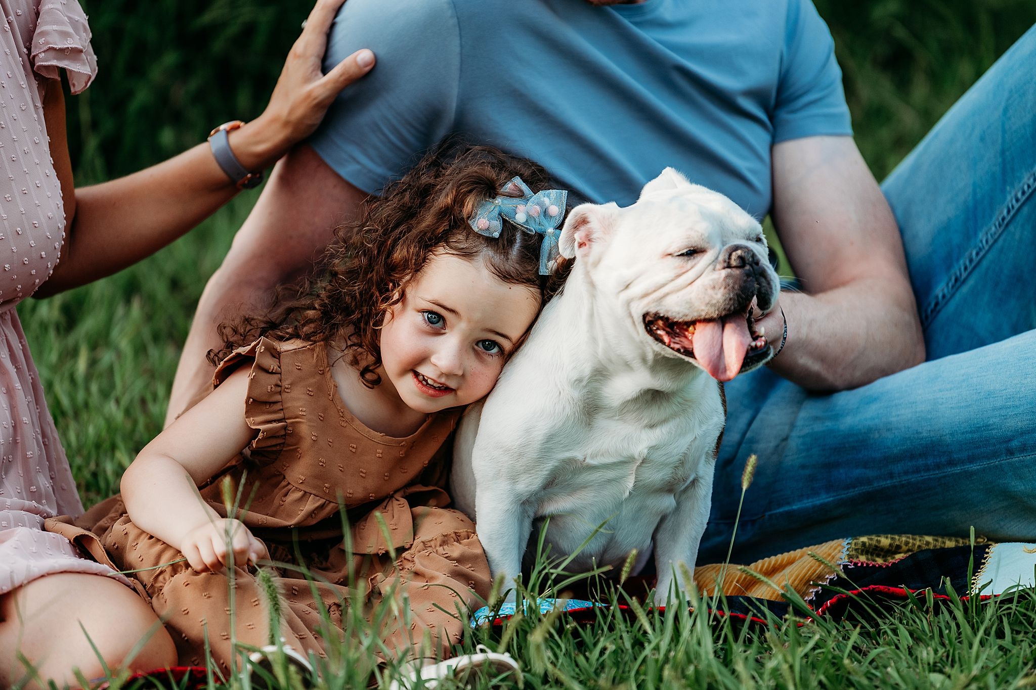 Five connected images showing a person in blue jeans playing and cuddling with a happy white husky dog in grass.