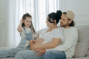 Family relaxing together on cozy white sofa in bright sunlit living room.