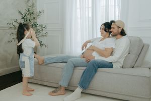 Side view of someone exercising with their toddler on a couch in a bright, modern living room.