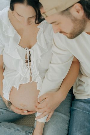 Intimate portrait series showing tender maternity moments between couple wearing white tops and jeans.