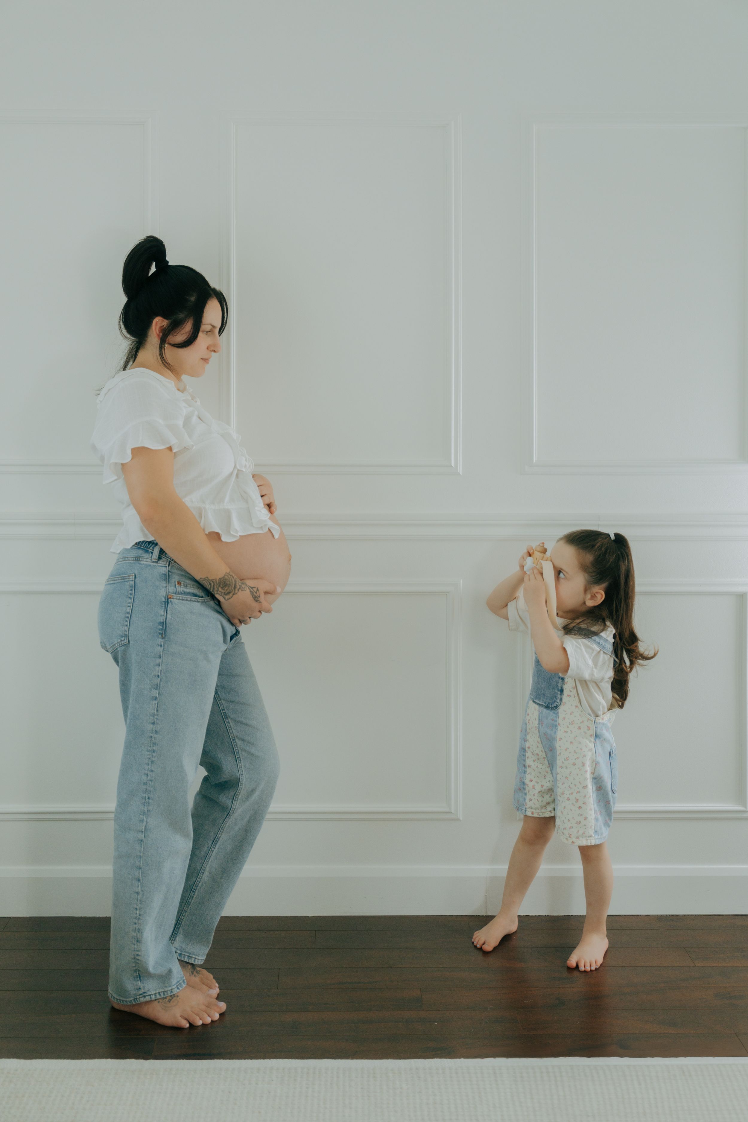 Parent and child playing together with expressive body movement against a white paneled wall.