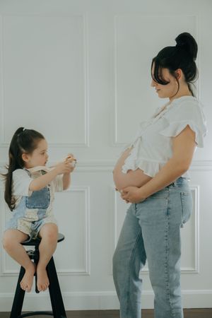 Parent and child engage in playful choreographed dance sequence wearing matching jeans against white wall background.