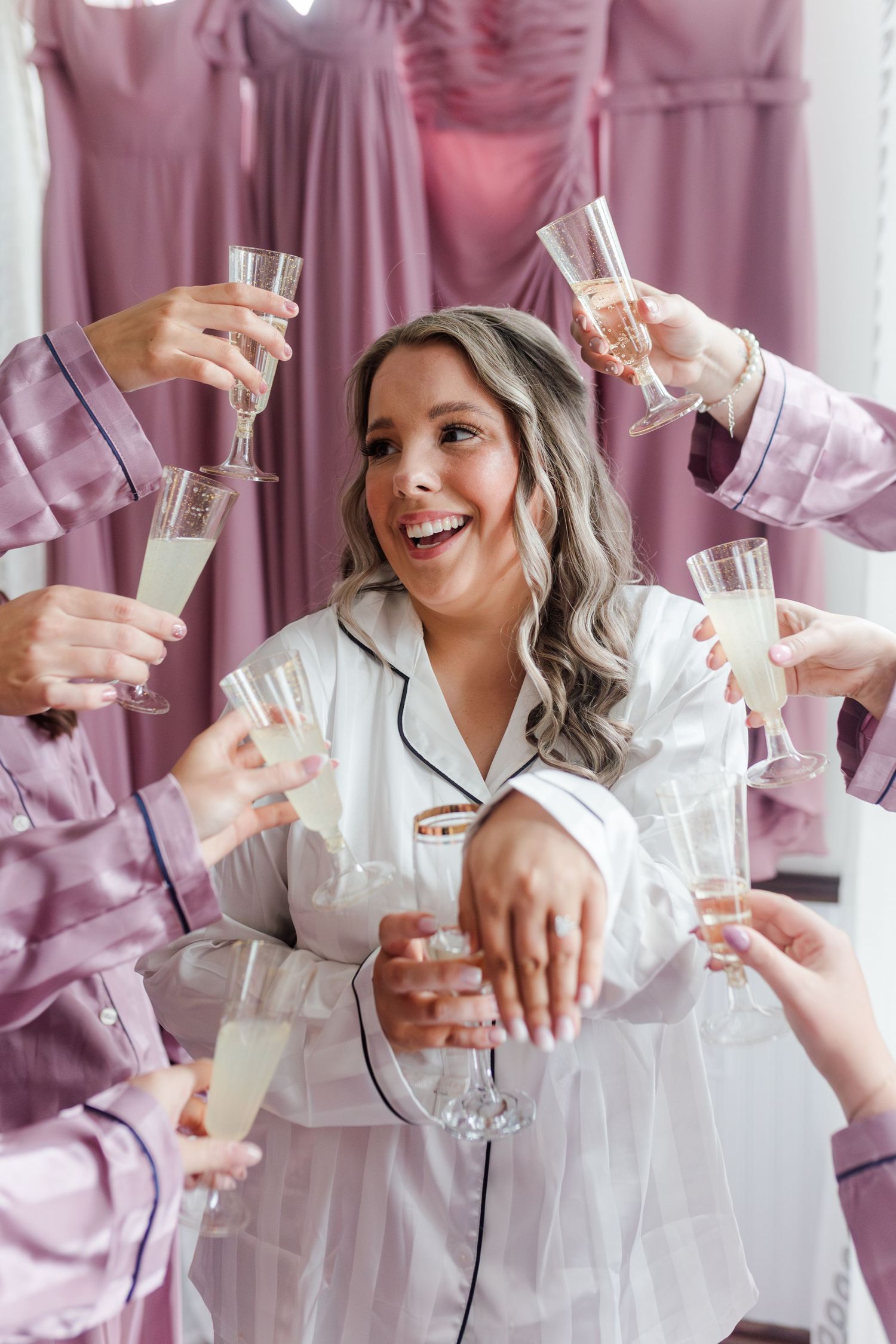 Wedding prep scene with white and pink robes as people gather to toast with champagne glasses.