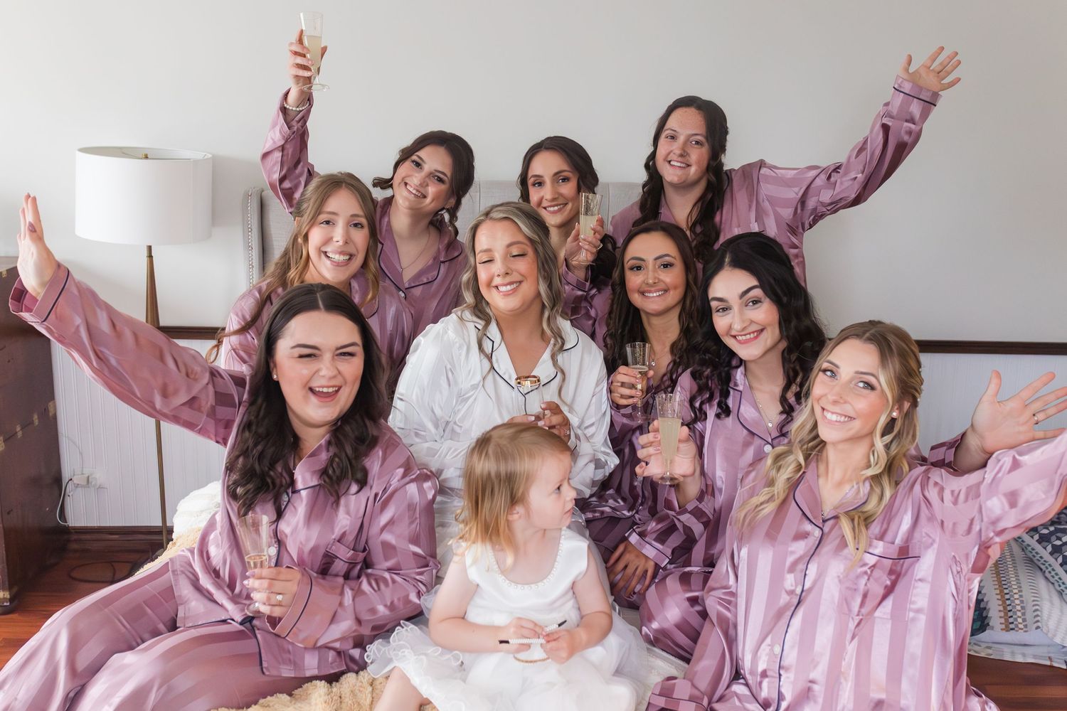 Group wearing matching pink silk robes pose together while celebrating a special occasion.