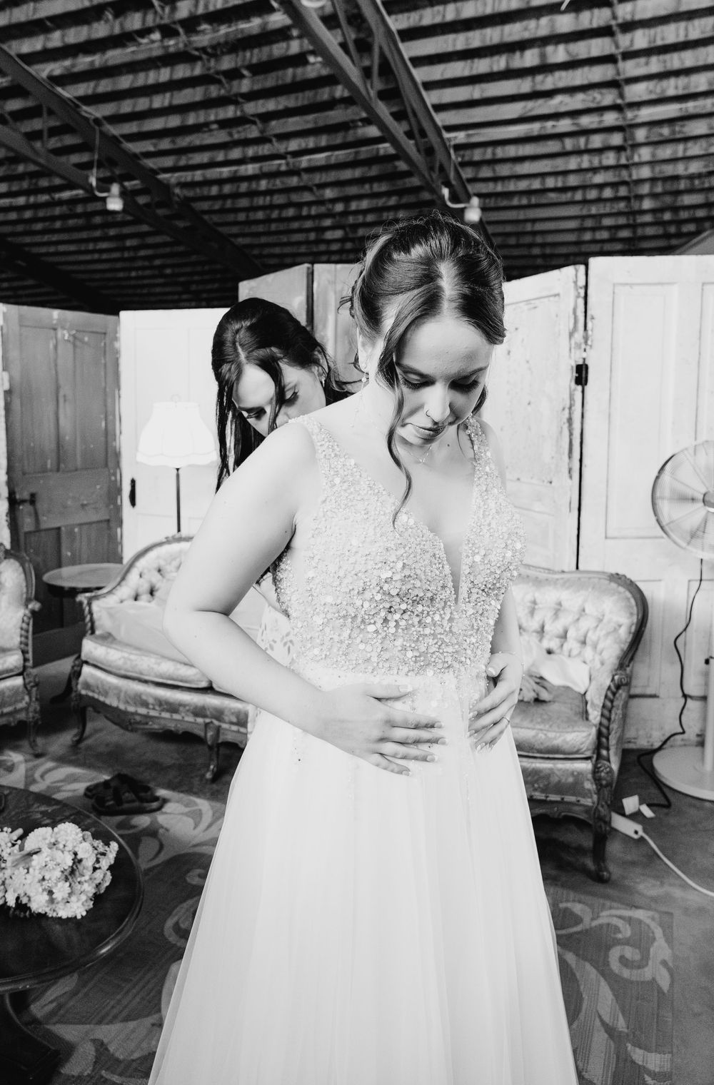 Black and white detail shots of a delicate lace wedding dress being fitted and adjusted.