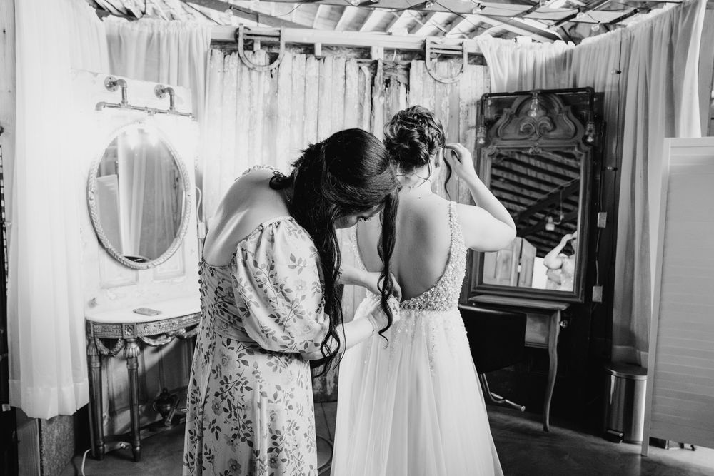 Black and white candid photo showing guests and wedding party preparing in an elegant dressing room.