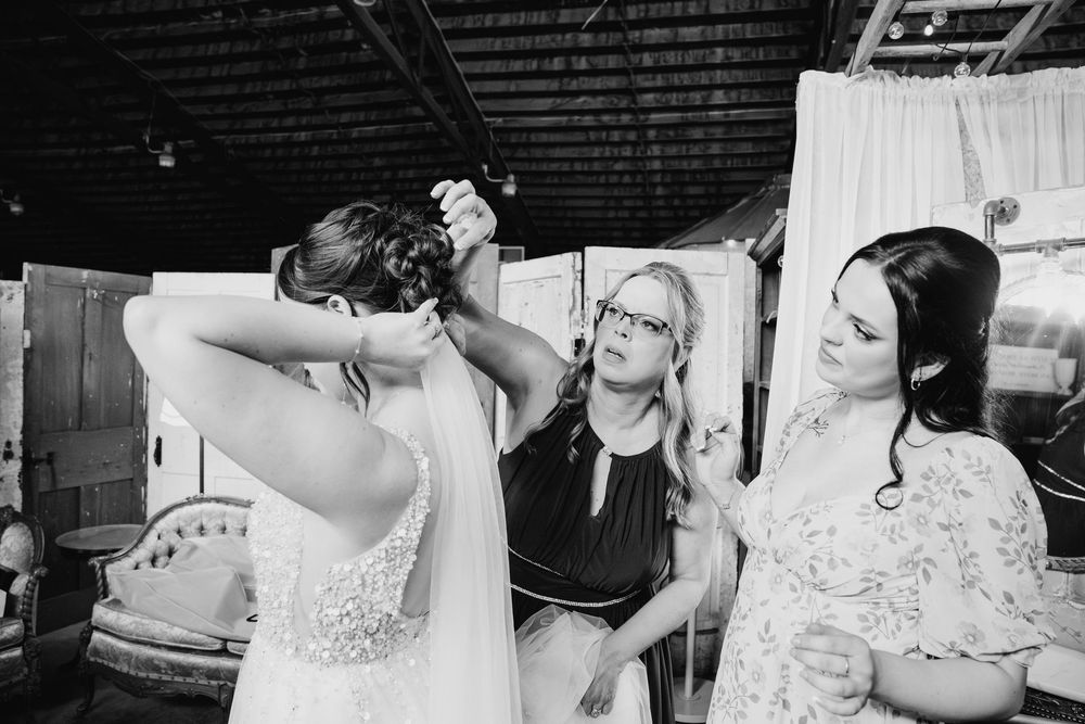 Black and white image of a wedding preparation moment showing final touches and adjustments in an industrial space.