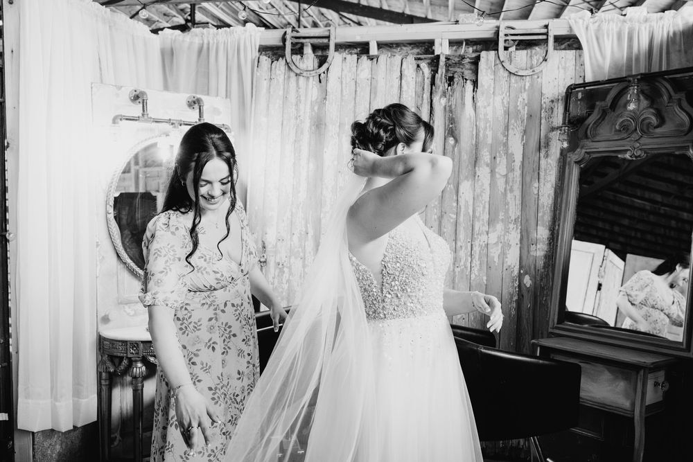 Several elegant white wedding dresses hang on display in a bridal boutique interior showing lace and tulle details.