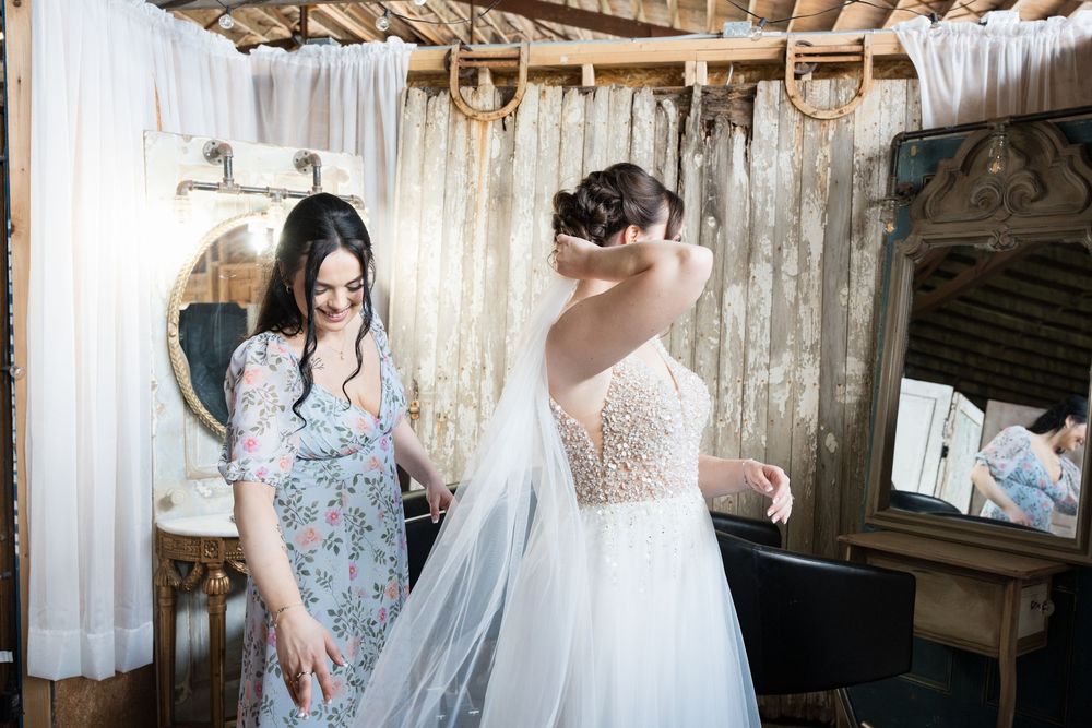 A bridal gown detail with delicate lace embellishments and buttons at a rustic barn venue.