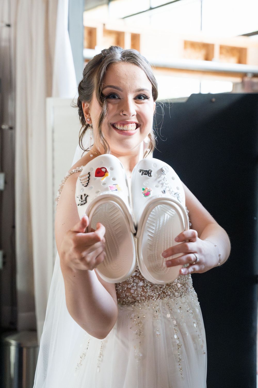 A person in a white dress holds paper cups decorated to resemble a bride's wedding attire.