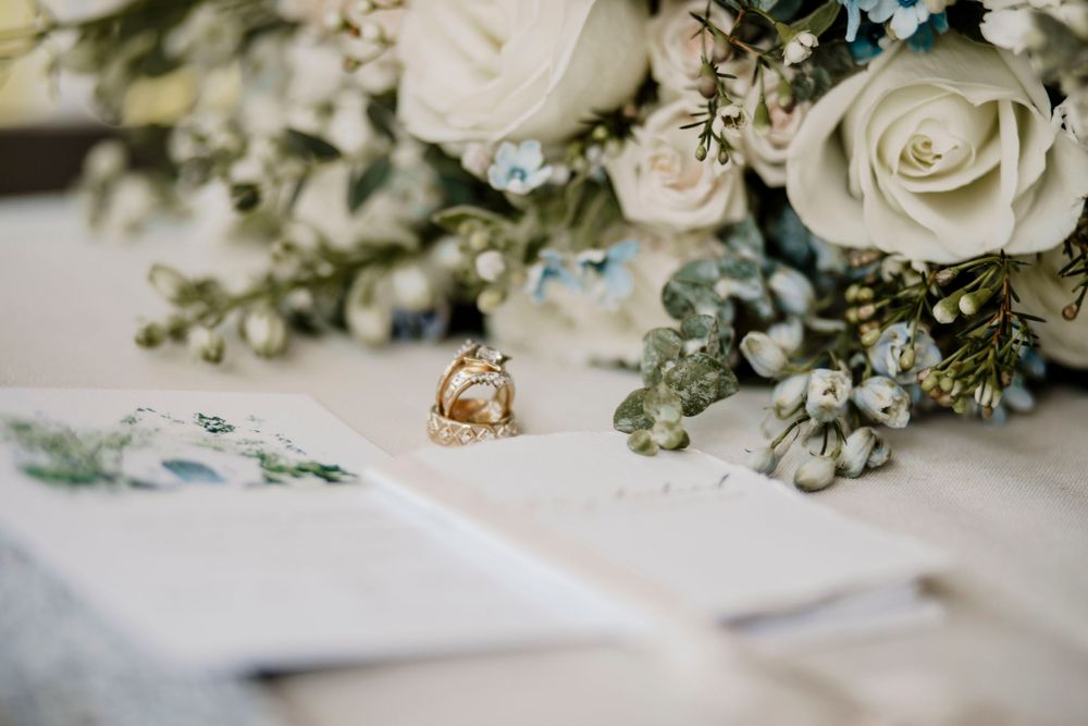 Wedding rings nestled among white roses and greenery bouquet.