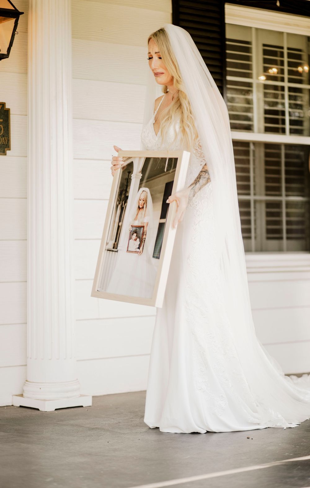 A bride in a flowing white dress and veil twirls gracefully across a white porch during a wedding photoshoot.
